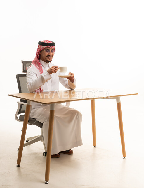 رجل سعودي بالزي التقليدي يشرب القهوة على مكتبه