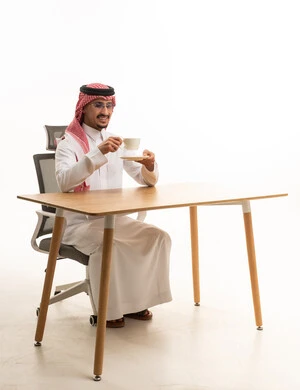 رجل سعودي بالزي التقليدي يشرب القهوة على مكتبه