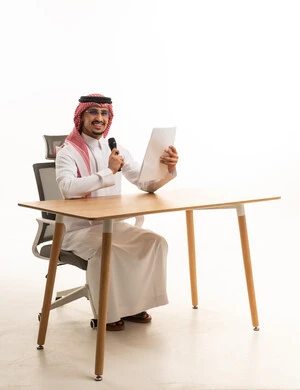 Saudi Businessman at Desk Holding Microphone and Paper