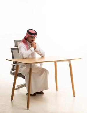 رجل أعمال سعودي يجلس في المكتب بوضعية تفكير