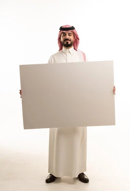 رجل سعودي بالزي التقليدي يمسك لوحة بيضاء فارغة