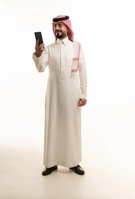 رجل سعودي بالزي التقليدي يستخدم الهاتف الذكي