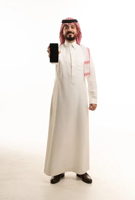 رجل سعودي بالثوب التقليدي يحمل هاتف ذكي