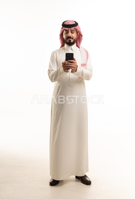 رجل سعودي بالزي التقليدي يستخدم هاتف ذكي