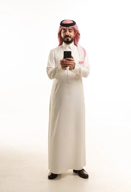 رجل سعودي بالزي التقليدي يستخدم هاتف ذكي