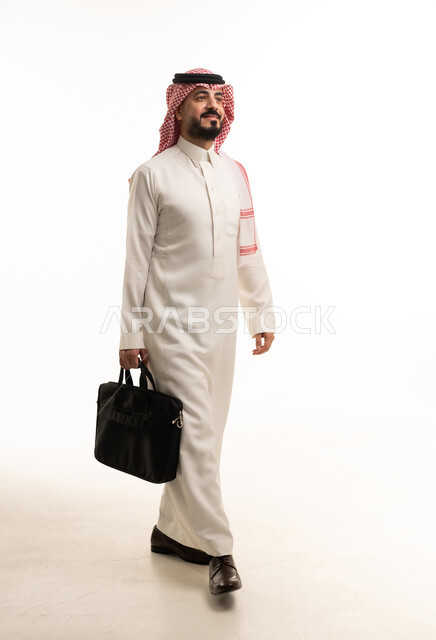 رجل أعمال سعودي يمشي مع حقيبة عمل بخلفية بيضاء