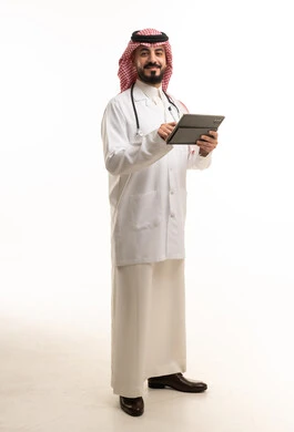 طبيب سعودي يحمل جهاز لوحي أمام خلفية بيضاء