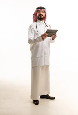 طبيب سعودي بالزي التقليدي يمسك جهاز لوحي رقمي