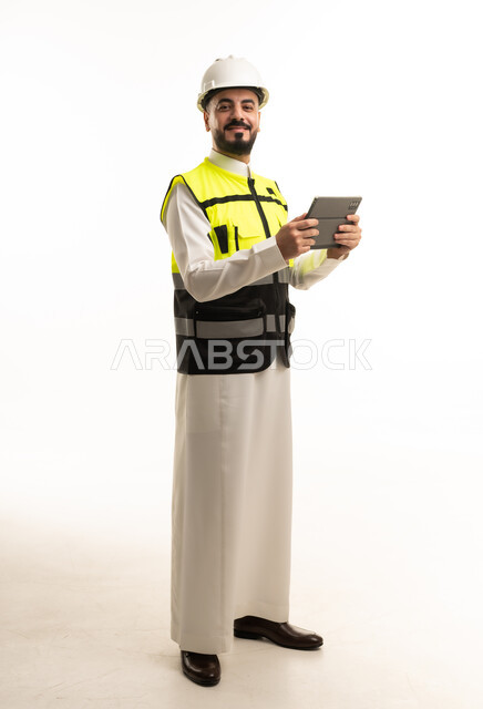 مهندس سعودي بالثوب والخوذة يمسك بجهاز لوحي