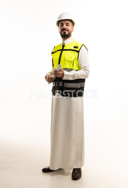 مهندس سعودي بالثوب وسترة السلامة يحمل مخططات هندسية