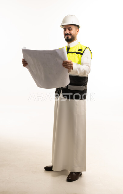 مهندس سعودي يحمل مخططاً هندسياً بزي السلامة