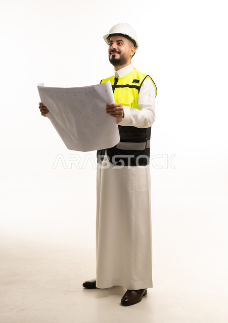 مهندس سعودي بالثوب التقليدي يحمل مخططات هندسية