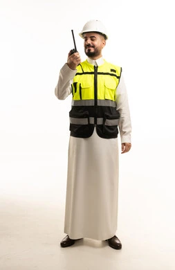 مهندس سعودي يرتدي سترة السلامة ويستخدم جهاز اللاسلكي
