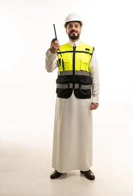 مهندس سعودي يرتدي سترة السلامة ويمسك بجهاز لاسلكي