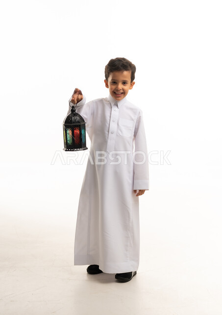طفل سعودي بالثوب التقليدي يحمل فانوس رمضان