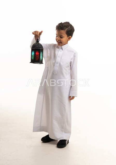 طفل سعودي بالثوب الأبيض يحمل فانوس رمضان