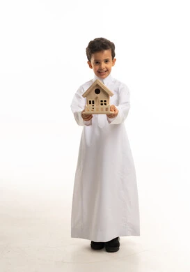 طفل سعودي بالثوب التقليدي يحمل مجسم منزل