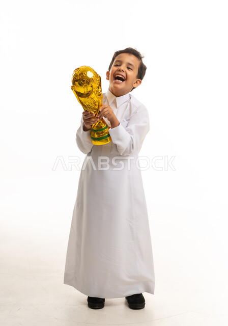 طفل سعودي بالثوب يحمل كأس ذهبي على خلفية بيضاء