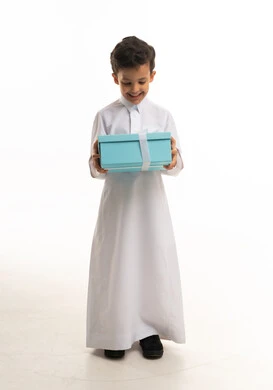 طفل سعودي بالثوب التقليدي يحمل علبة هدية زرقاء