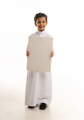 طفل سعودي بالثوب التقليدي يمسك بلوحة فارغة