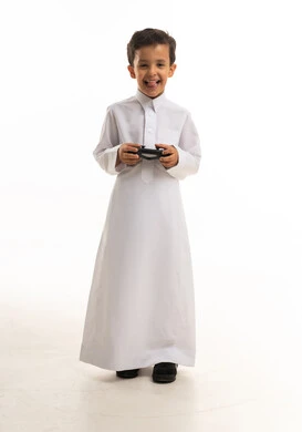 صبي سعودي بالثوب التقليدي يحمل يد تحكم ألعاب