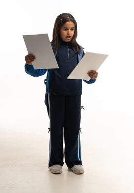 طالبة سعودية متفاجئة تمسك أوراقا في الاستوديو