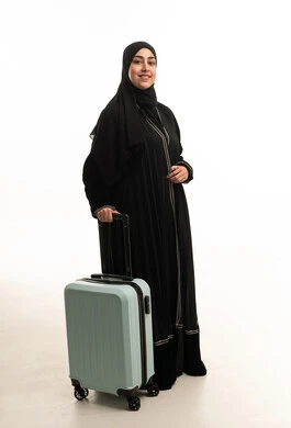 امرأة إماراتية بالعباءة السوداء مع حقيبة سفر