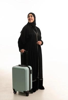امرأة سعودية بالعباءة مع حقيبة سفر على خلفية بيضاء