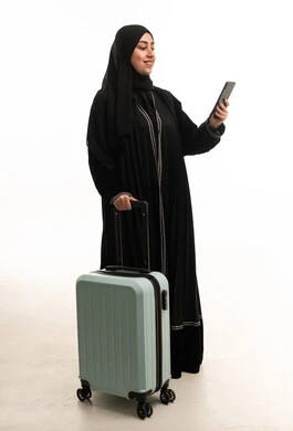 امرأة سعودية مسافرة مع حقيبة سفر وهاتف ذكي