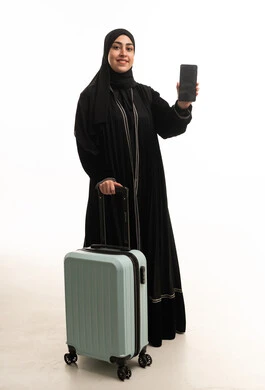 امرأة سعودية مع حقيبة سفر وهاتف ذكي خلفية بيضاء