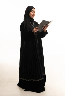 امرأة سعودية بالعباءة السوداء تقرأ كتاباً