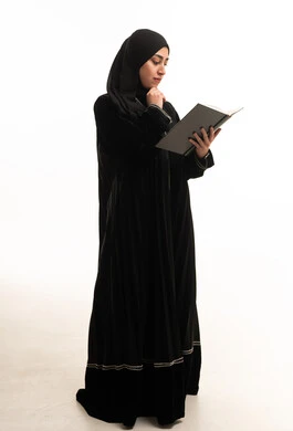 امرأة سعودية بالعباءة تقرأ كتاباً في الاستوديو