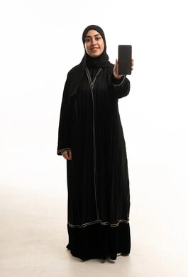 امرأة سعودية بالعباءة السوداء تحمل هاتف ذكي