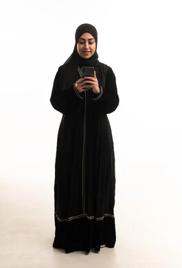 امرأة سعودية بالعباءة السوداء تستخدم الهاتف الذكي