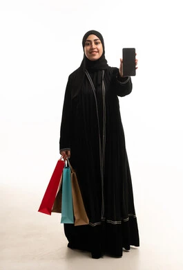 امرأة إماراتية مع حقائب تسوق وهاتف ذكي