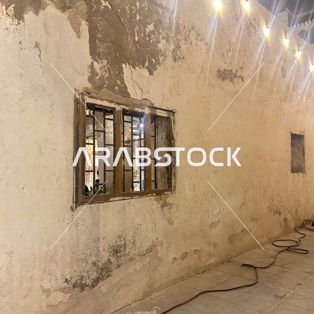 جدار حجري قديم ونافذة في جدة التاريخية ليلاً