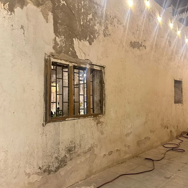 جدار حجري قديم ونافذة في جدة التاريخية ليلاً