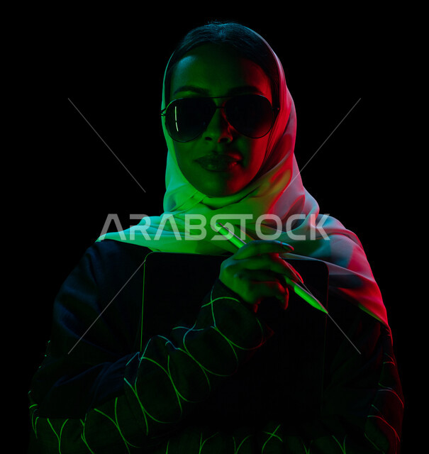 بورتريه لمرأة عربية سعودية خليجية تحمل بيدها جهاز التابلت المحمول , تصفح الانترنت , التسويق الالكتروني , التواصل مع الأصدقاء , اجتماع عمل , الرسم على جهاز التابلت , الدراسة عن بعد , استخدام التقنية الحديثة , خلفية سوداء .