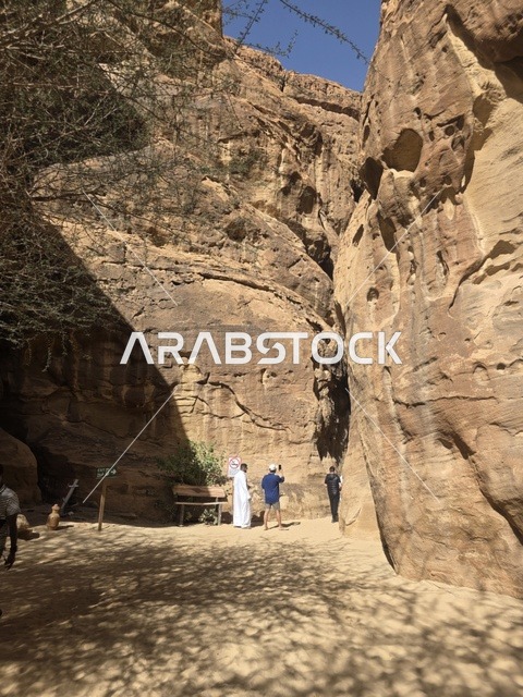 سياح في ممر جبلي صخري بمنطقة العلا السعودية