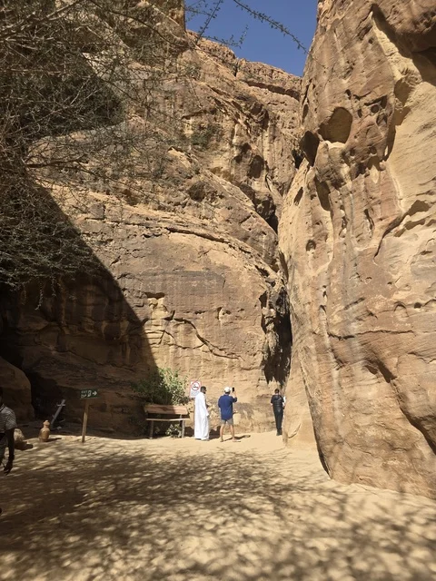 سياح في ممر جبلي صخري بمنطقة العلا السعودية