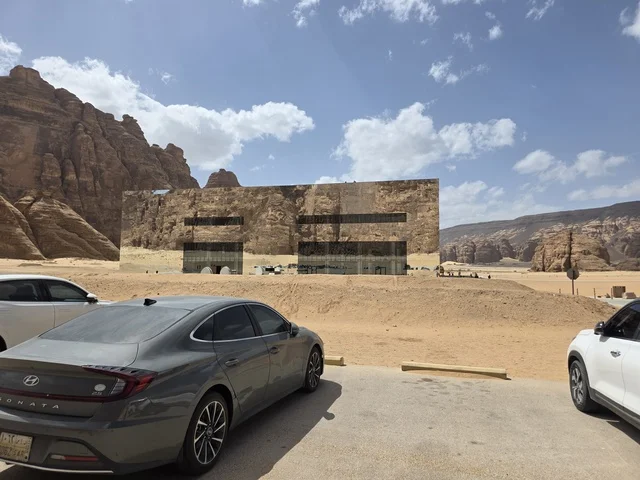 The Miraya building is located in the desert landscape of Wadi Ashar in the Al-Ula region of Saudi Arabia. The glass facade reflects the surrounding sandy mountains and the blue sky during daylight hours. The Miraya building is located in the desert landscape of Wadi Ashar in the Al-Ula region of Saudi Arabia. The glass facade reflects the surrounding sandy mountains and the blue sky during daylight hours.