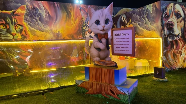 تمثال قطة وجداريات حديقة العجائب في الجبيل ليلاً