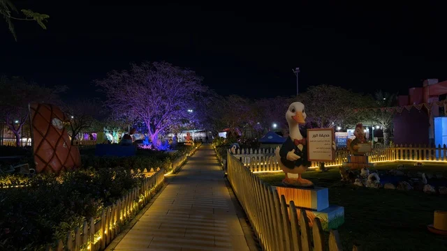 حديقة العجائب الجبيل مع الأشجار والممرات المضاءة ليلاً