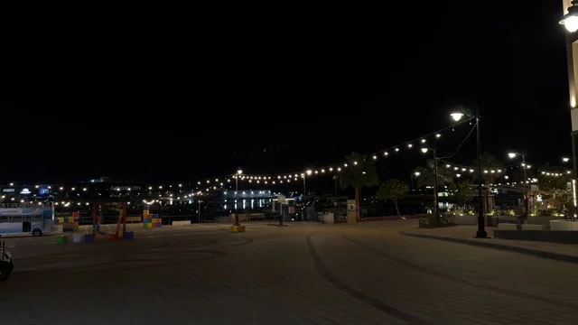 منظر ليلي لفعالية ألوان الجبيل على الممشى البحري في المملكة العربية السعودية. تضيء حبال الزينة الممشى المخصص للمشاة بجانب المباني السكنية الحديثة وأشجار النخيل.