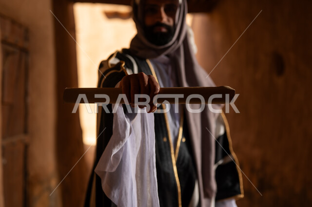 Saudi Man in Traditional Bisht Holding Scroll Old Building