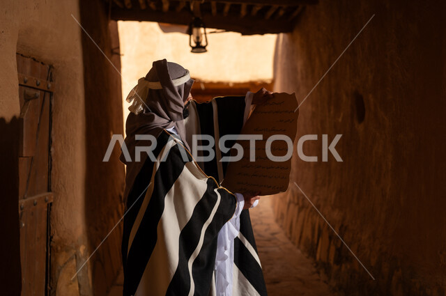 رجل سعودي يقرأ مخطوطة قديمة في ممر تراثي