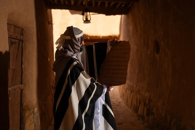 رجل سعودي يقرأ مخطوطة قديمة في ممر تراثي