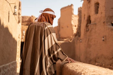 رجل سعودي بالزي التقليدي في قرية طينية قديمة