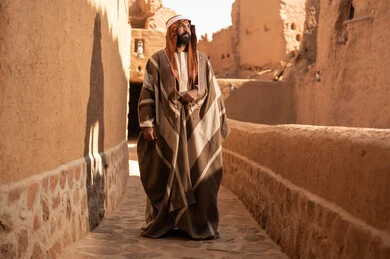 رجل سعودي بالبشت التقليدي في قرية تراثية طينية