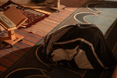Arab Man Praying in Mosque with Quran Stand